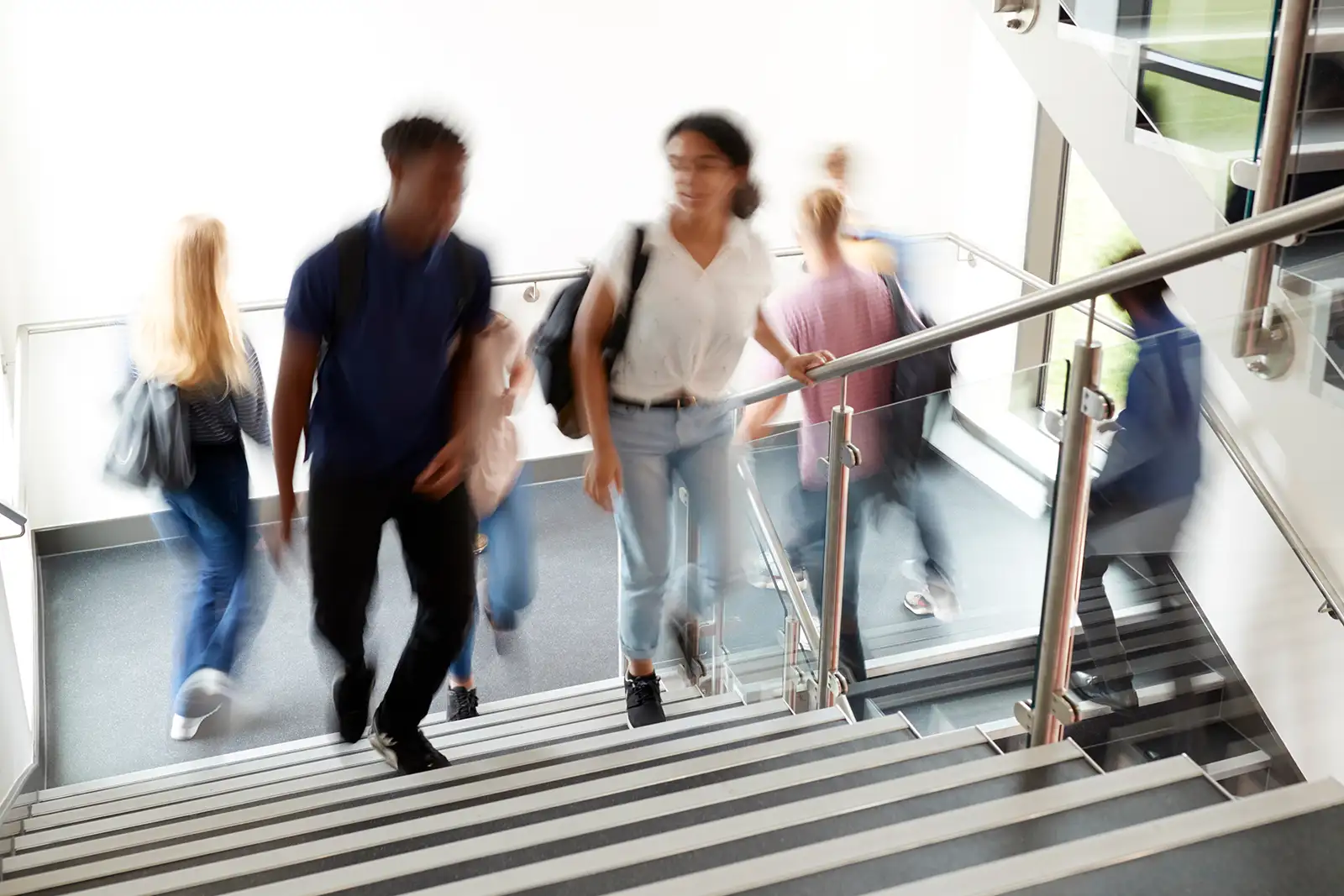 Teenage students climb a stairway at a high school with a slight motion blur