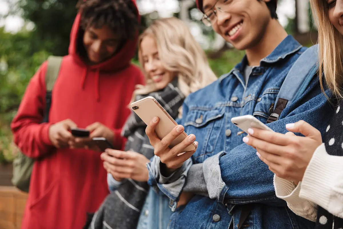 A group of young adults looking at their smart phones.