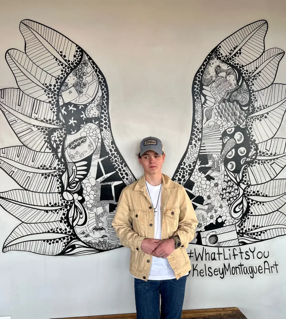 Sam Aden standing in front of a mural of angel wings