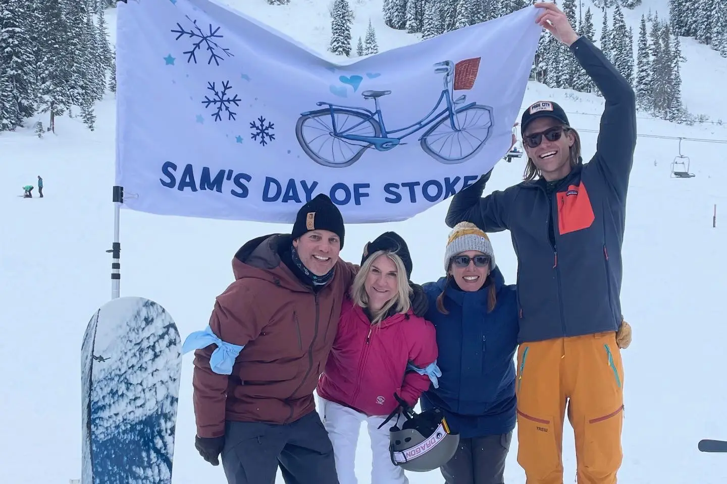 Jim Licko, Laura Love, Ramonna Robinson and Jon Woods holding up the Sam's Day of Stoke flag at Sam's Day of Stoke 2025