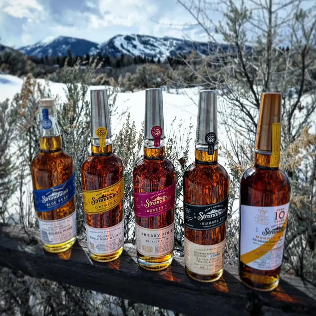 Different bottles of Stranahan's lined up with the mountains in the background